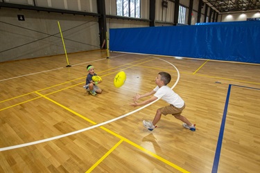 Two young children catch each others footballs