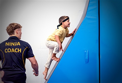 Ninja participants climbing vertical wall