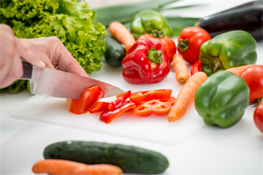 Staff slicing up a capsicum, with other fresh vegetables nearby