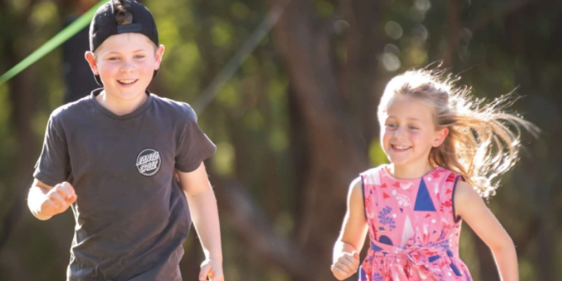 Two children running towards the camera with smiles on their faces