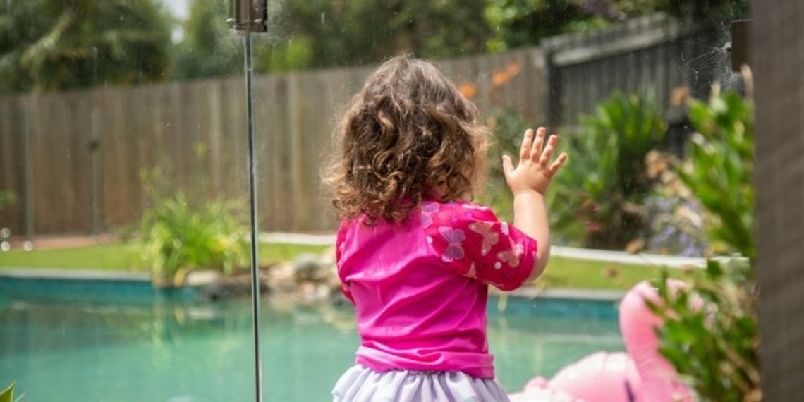 young girl standing at pool gate