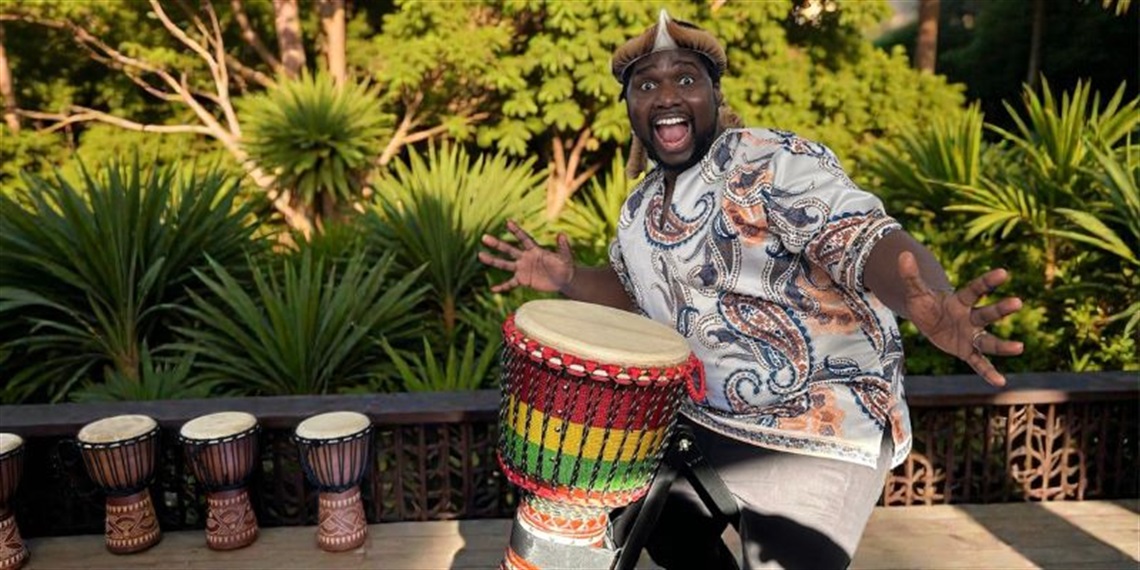 African drumming performer demonstrating a drum during a workshop.