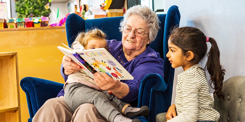 senior lady reading to two children