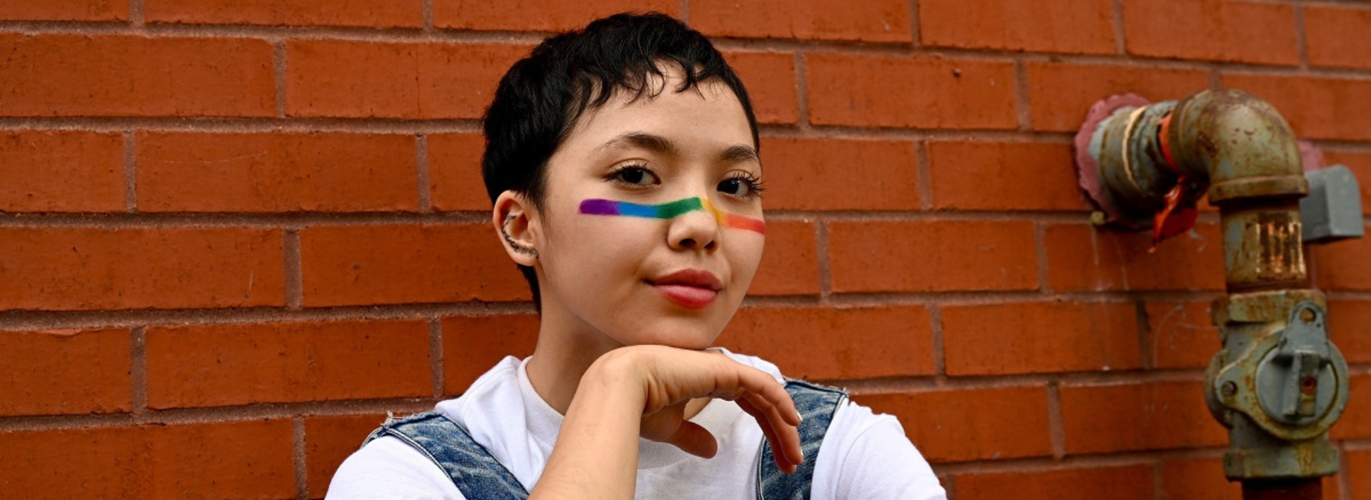 Young person with rainbow colours painted across their nose and cheeks