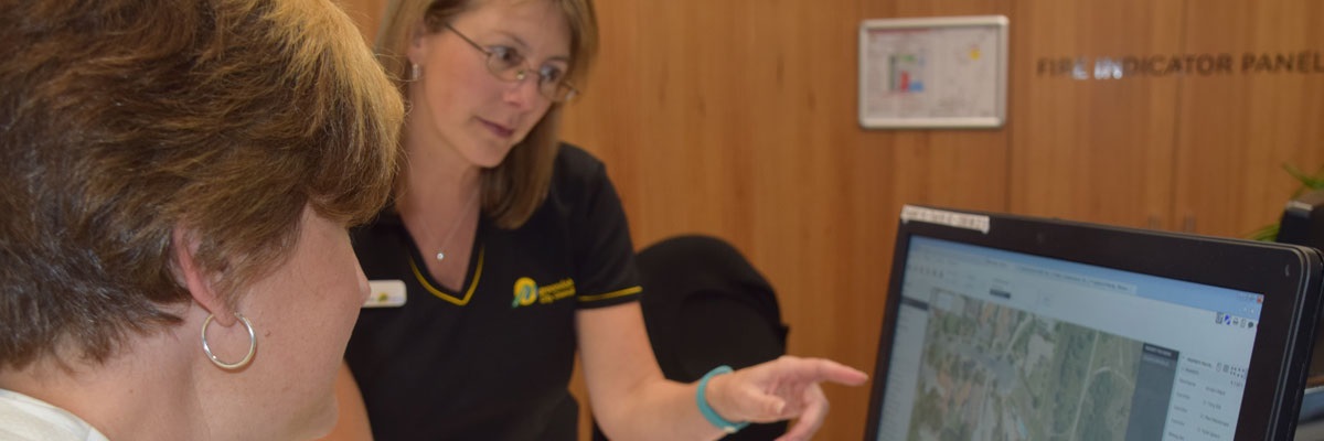 A customer service representative assisting a community member, showing them a map on the computer