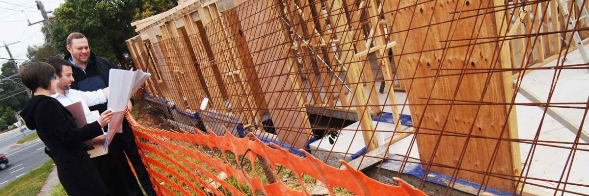 Engineering professionals looking at plans beside building site