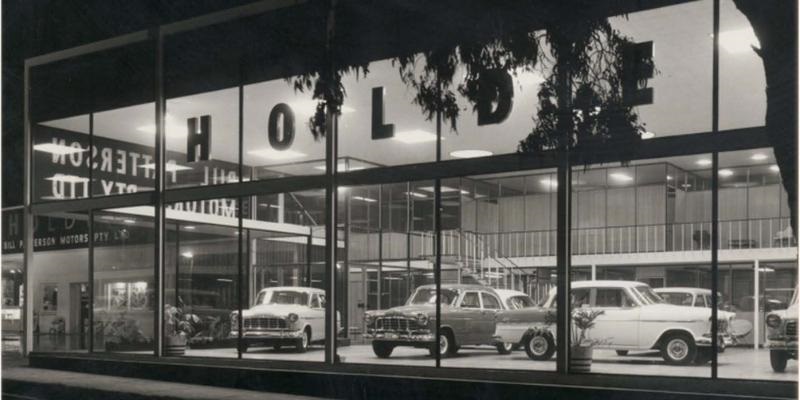 Black and white photo of classic cars sitting inside Bill Patterson Motors in 1959