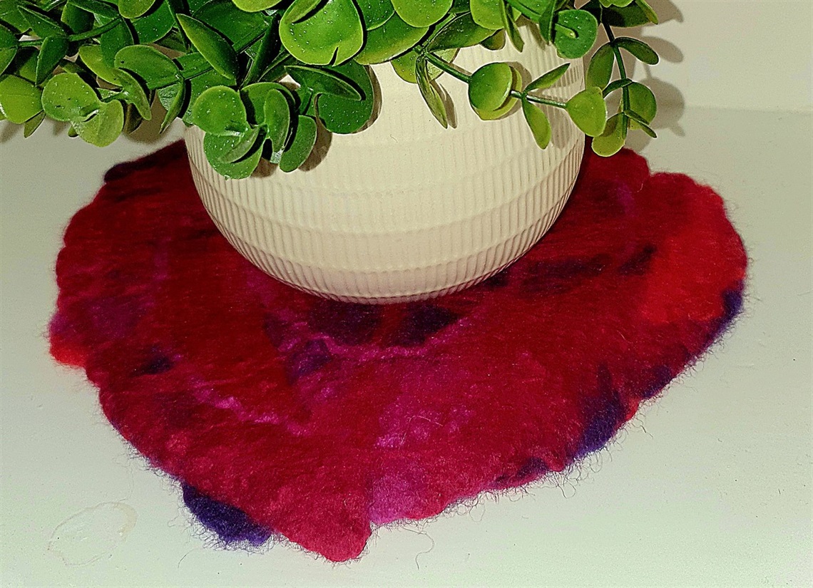 Bright pink and purple felt placemat beneath a plant pot.