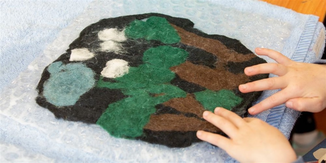 A child's hands moving felt to create a picture