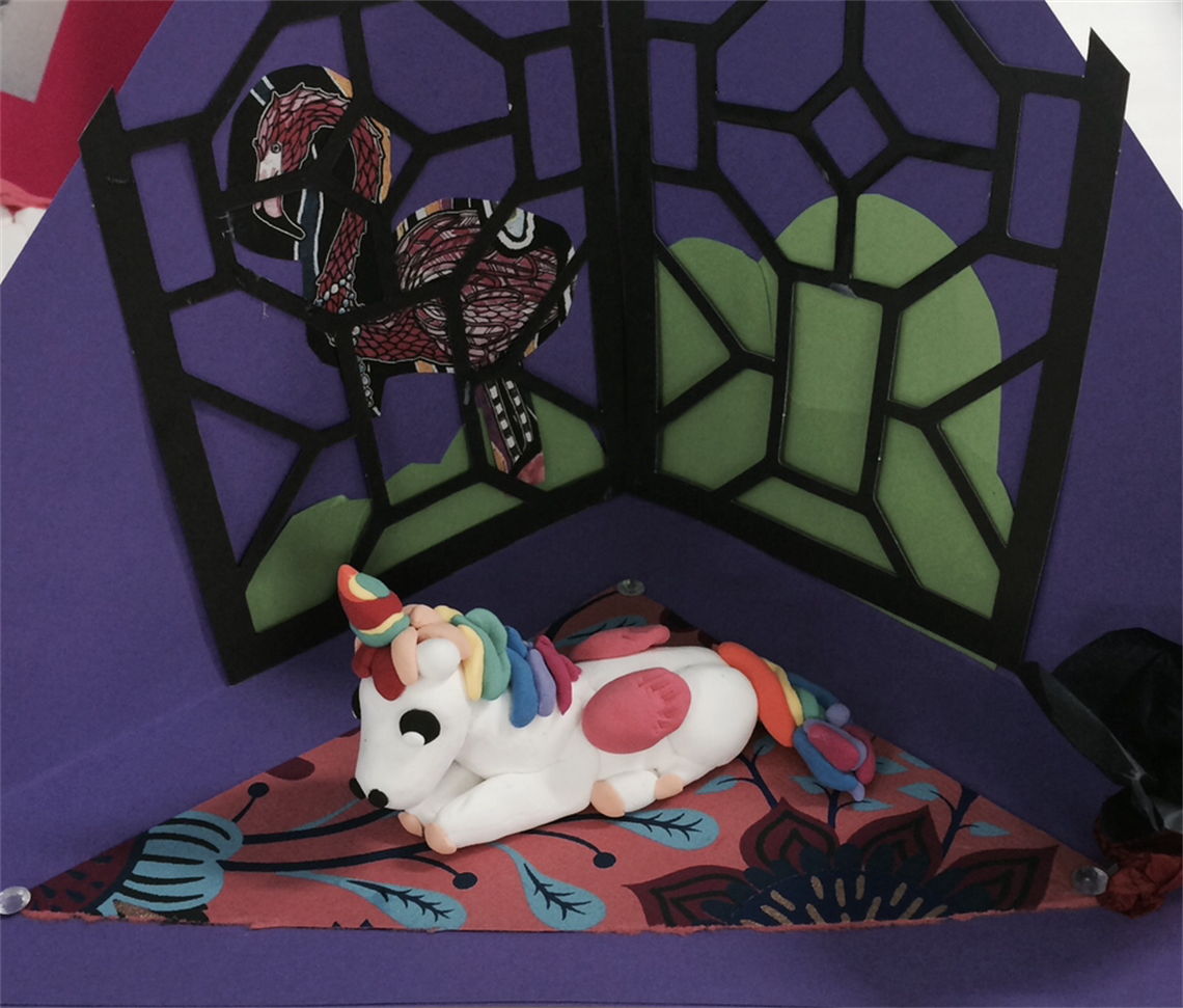 Handmade unicorn diorama with stained-glass-style dragon window and colourful patterned floor