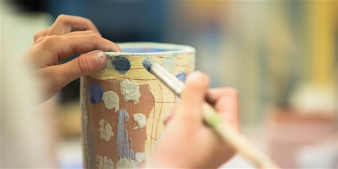 A hand painting onto a tumbler