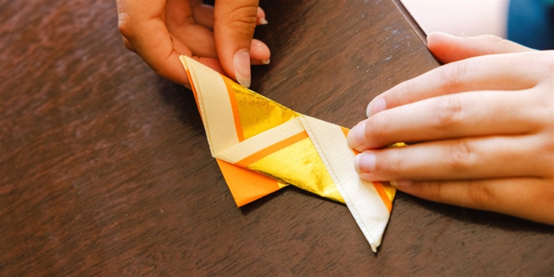 Hands folding paper into origami. Photo by Pia Johnson
