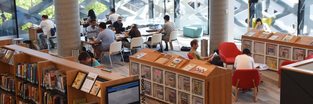 Library in Realm, with people look at the bookshelves, reading books and working on laptops.