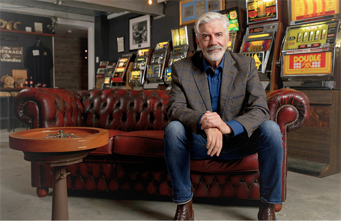 Person seated on a red leather couch in front of vintage poker machines.
