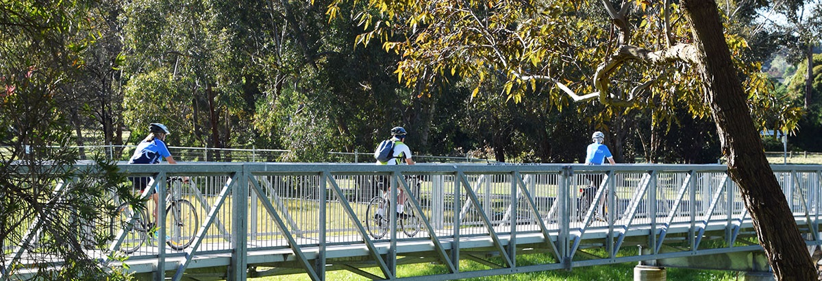 3 cyclists riding their bicycles along a metal bridge