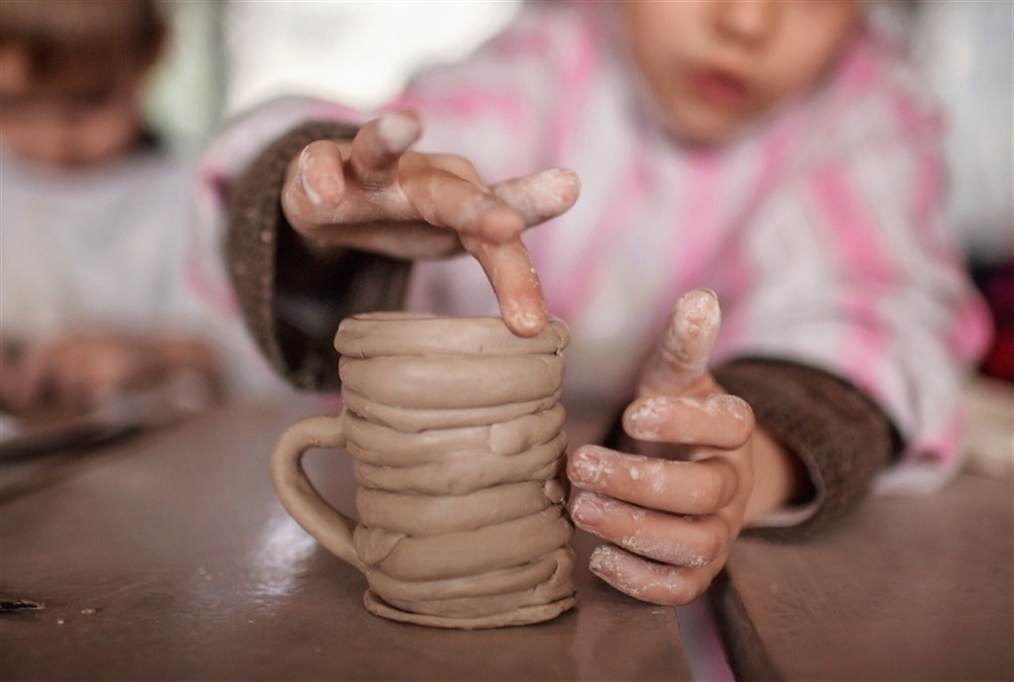 A child creating a mug out of clay