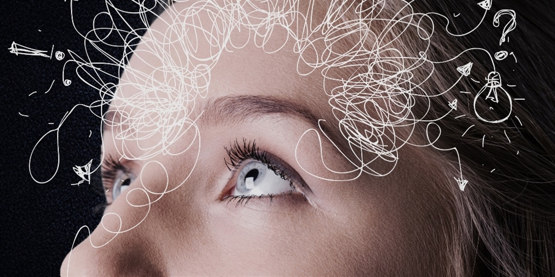 A close up of a persons eyes looking up. White scribbles and shapes are drawn over their forehead.