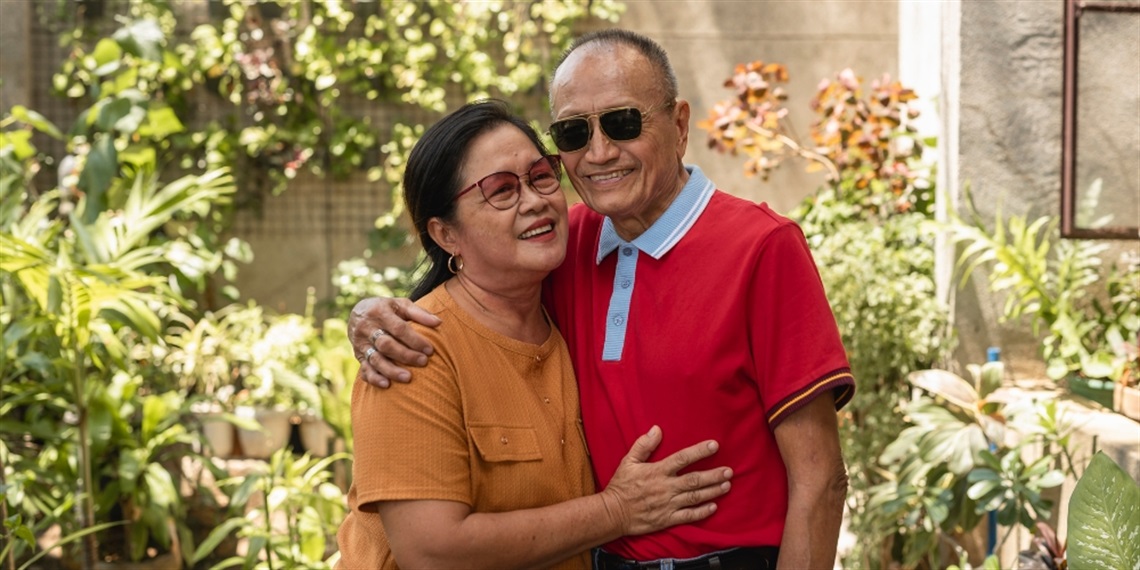 An older couple hugging in a garden