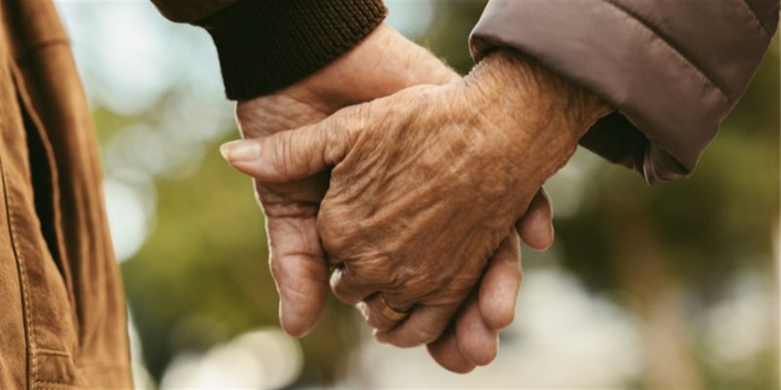 two older people holding hands