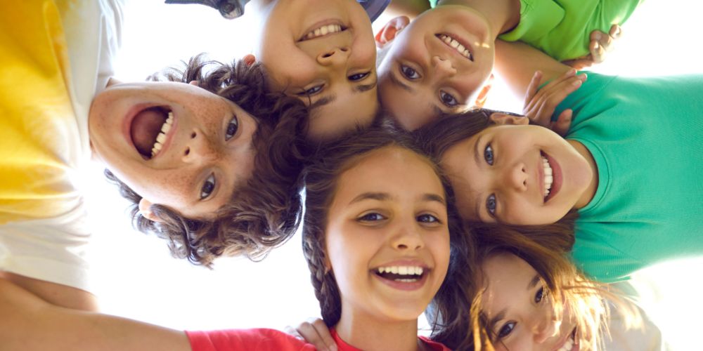6 young people in a circle smiling down at the camera