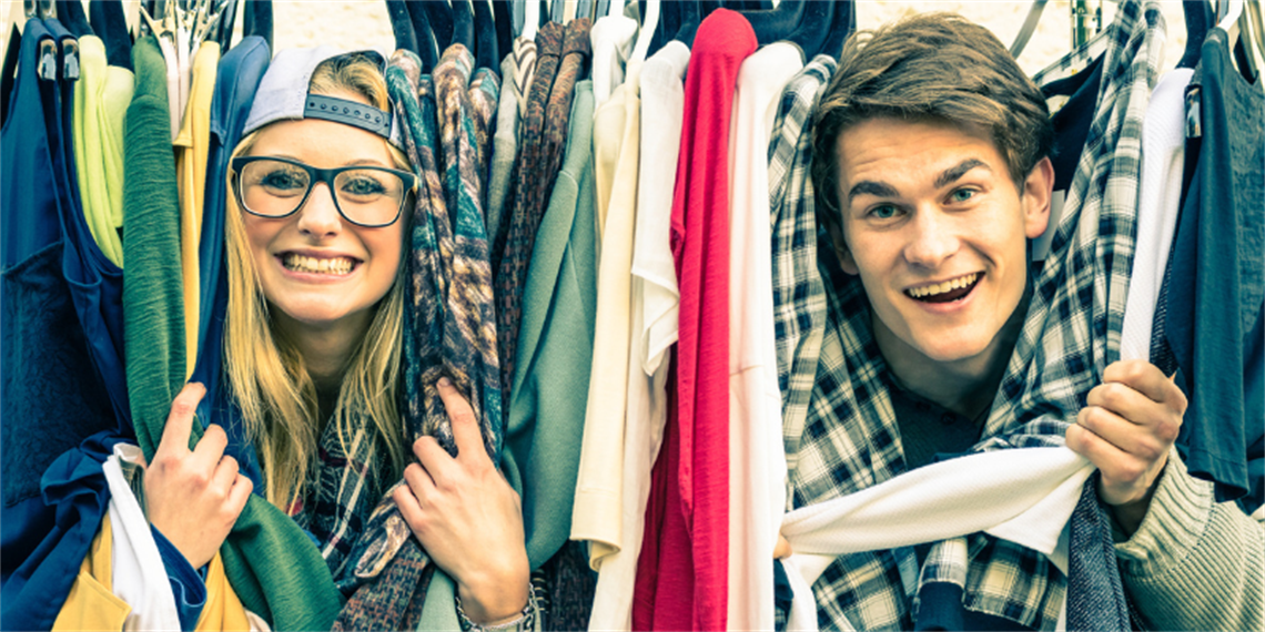 Couple smiling through a rack of clothing.png