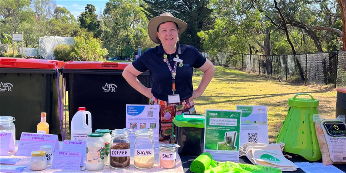 Person outside standing in front of tables with waste displays.png