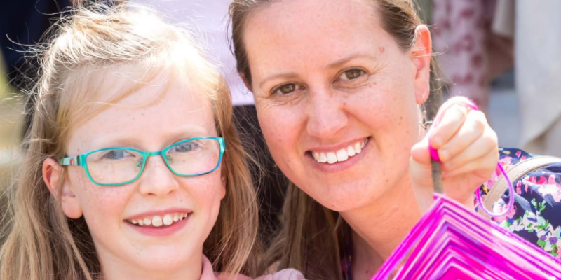 Close up photo of a parent and child smiling at the camera