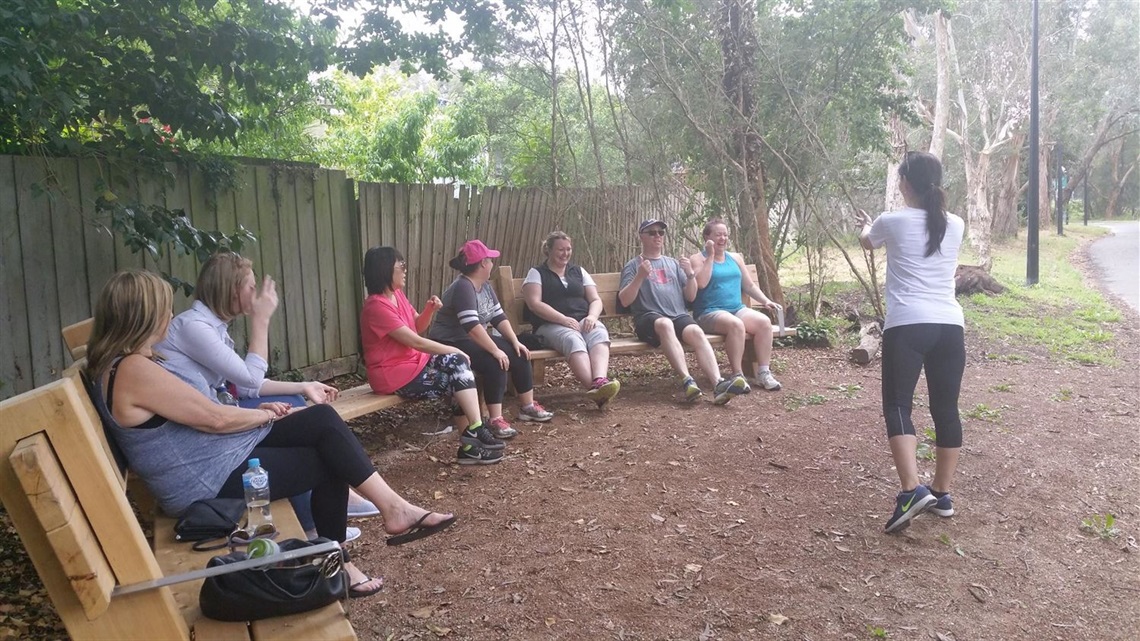 Carers sitting on wooden benches in a natural setting while the guest walker talks about the route they will be walking