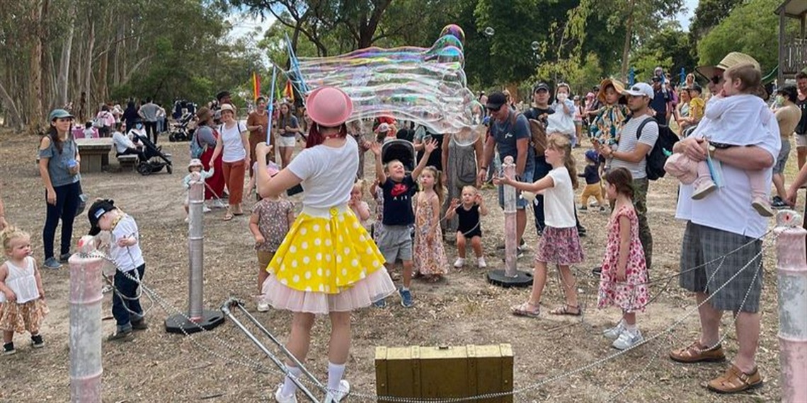 Entertainer creating massive bubbles for onlooking children and families to play with.
